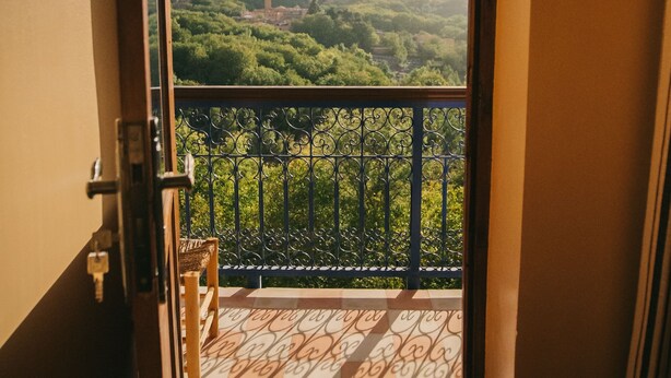 Un balcón con vistas a una montaña y vegetación.