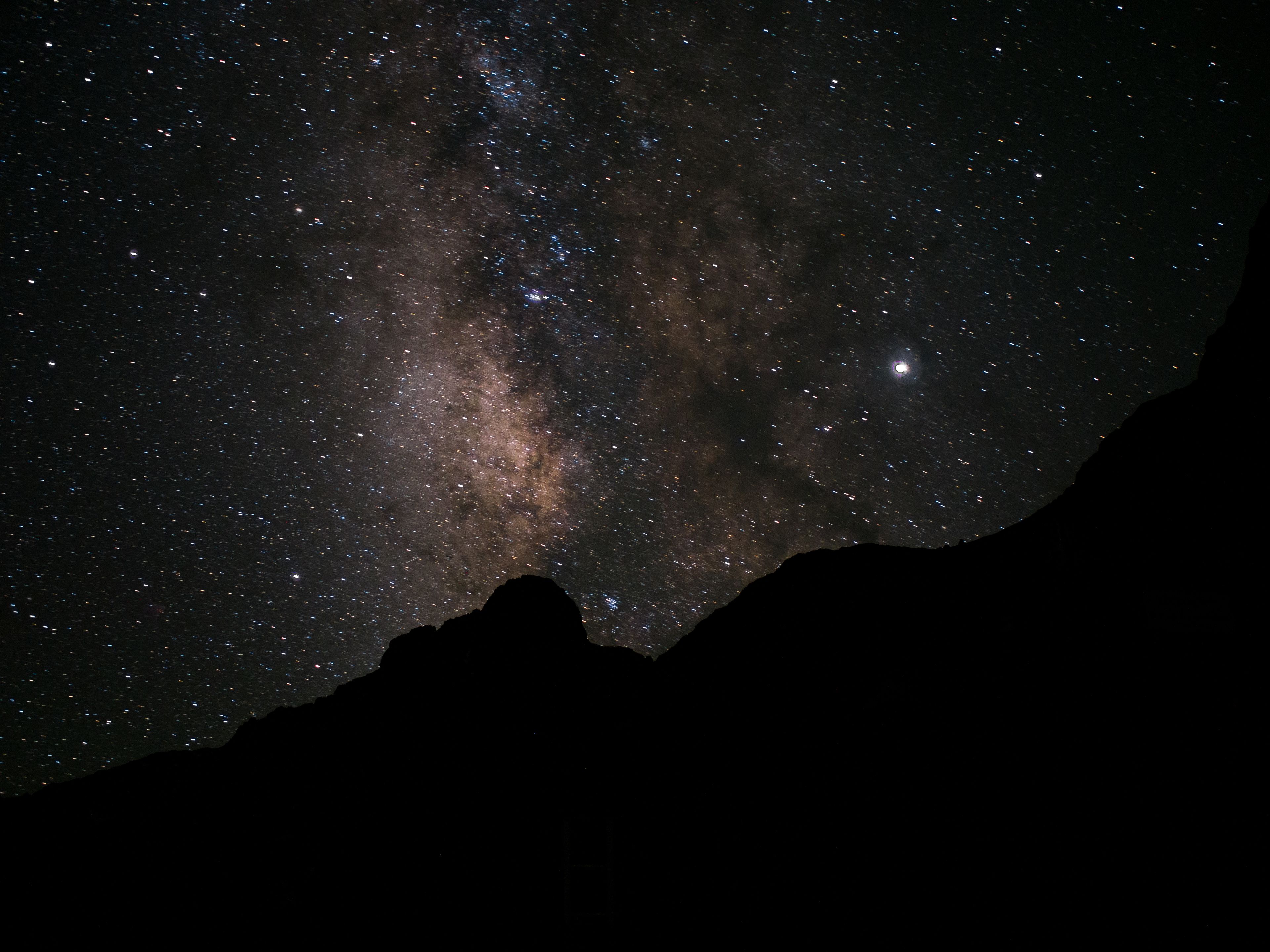 A night sky filled with stars and the Milky Way, viewed from a mountainous area.