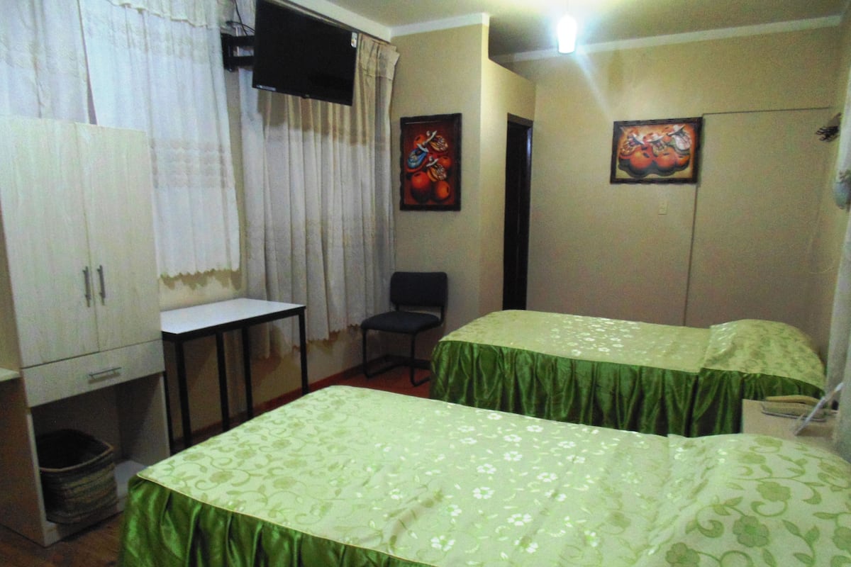 A room with two beds, a desk, a chair, and a wardrobe.