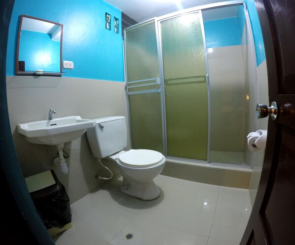 A bathroom with a white sink, toilet, and a glass shower enclosure.
