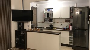 Una cocina moderna con televisor de pantalla plana, electrodomésticos integrados y una pequeña isla.