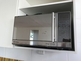 Un horno microondas SOMELA Mirage 2600DM de acero inoxidable montado sobre un mueble blanco.