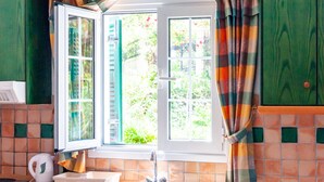 Una cocina con ventana, un lavabo y una tetera.