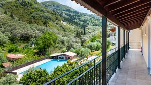 Un balcón con vistas a una piscina, rodeado de vegetación exuberante y colinas.