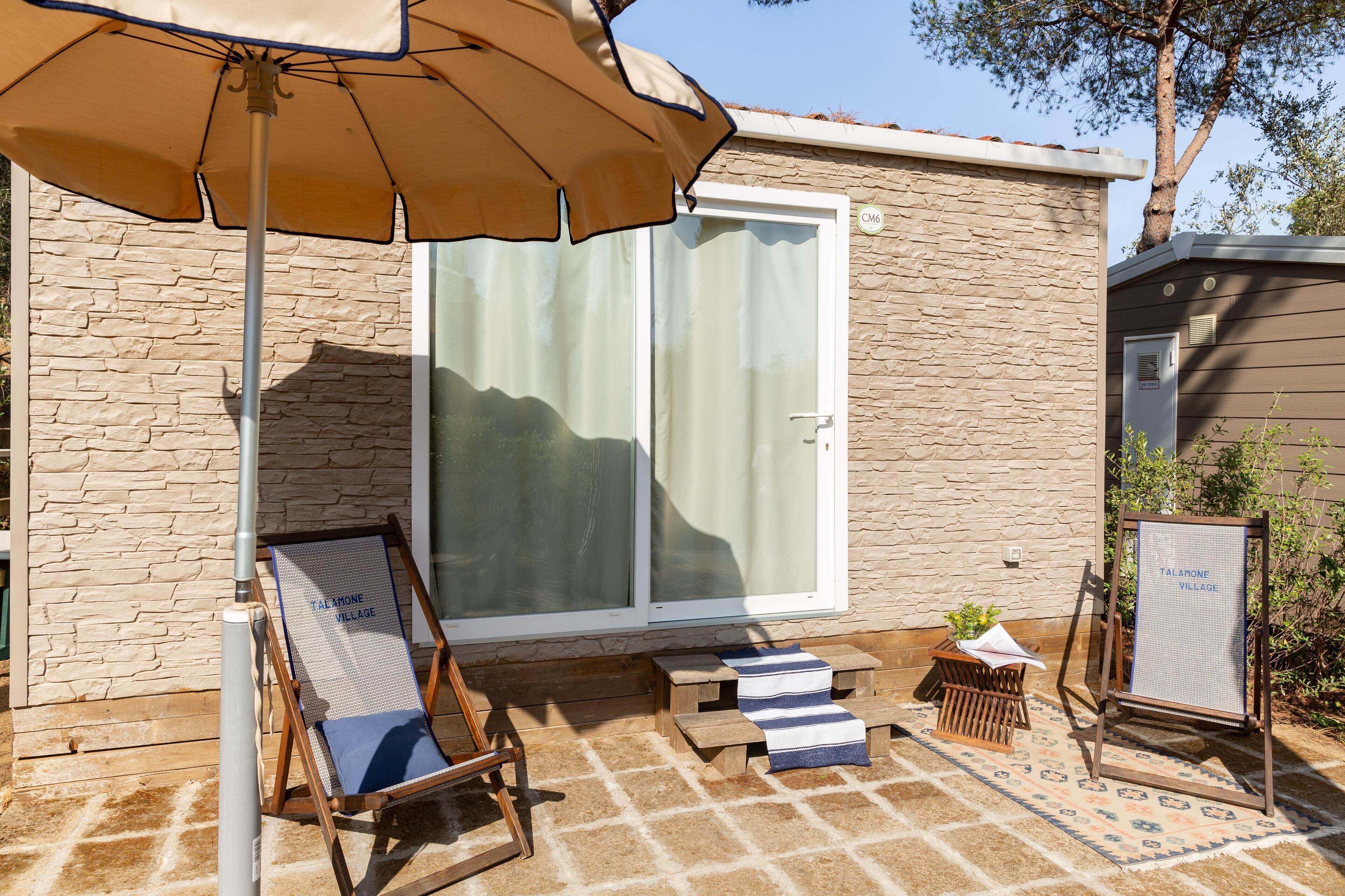 A patio area with a lounge chair, a small table, and a sign reading "TALAHOME VILLAGE".