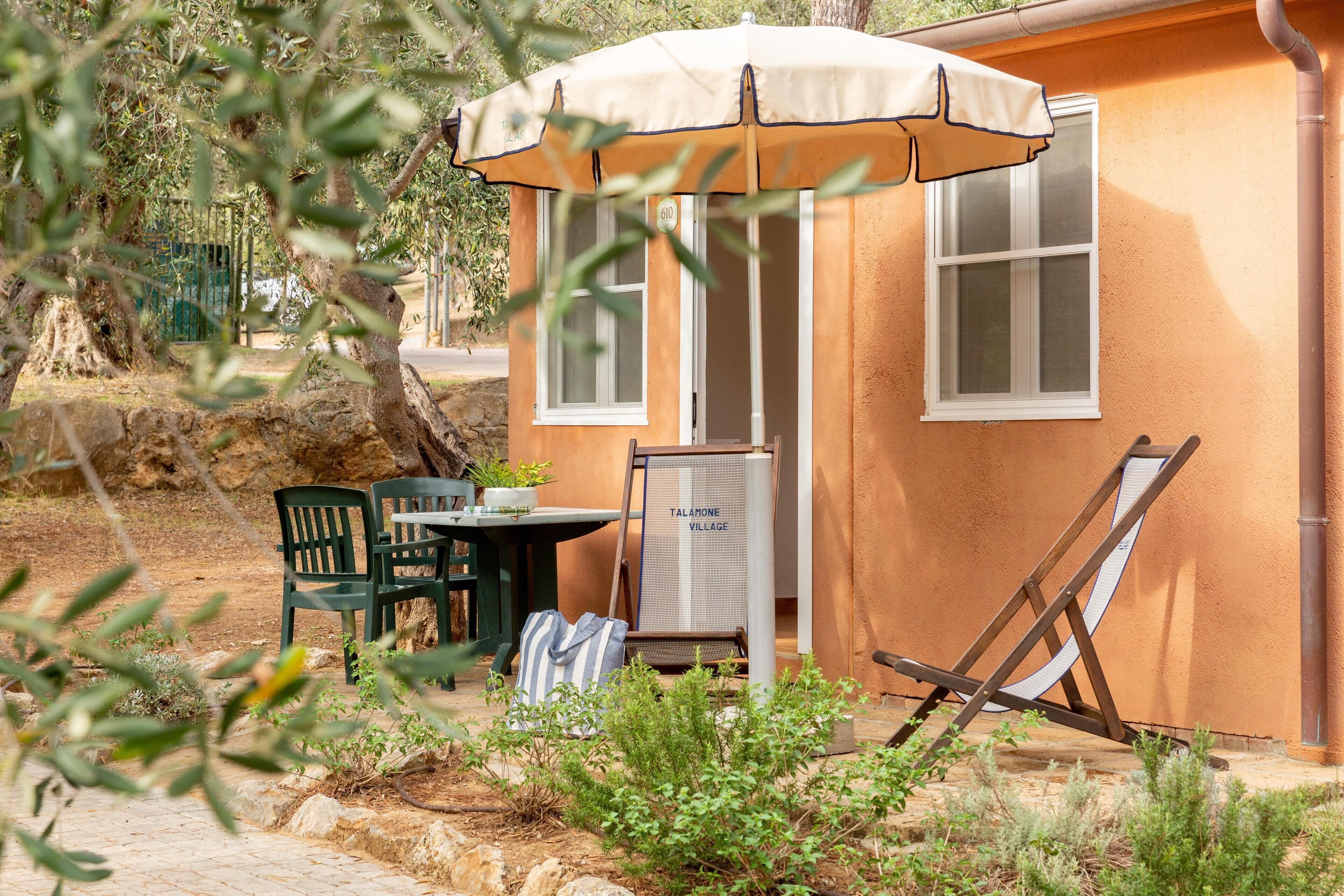 A small outdoor seating area with a table, chairs, and a signboard.