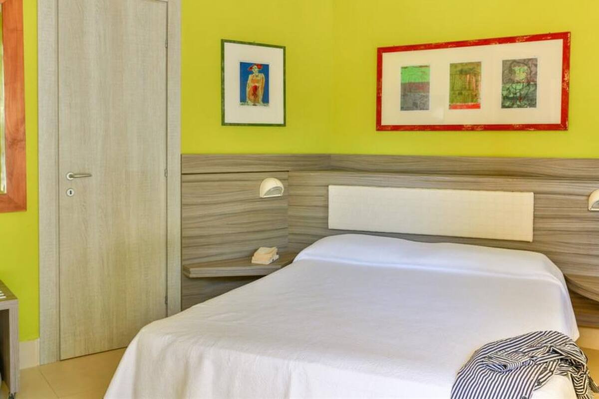 Une chambre à coucher avec un lit, une porte et deux tableaux encadrés au mur.