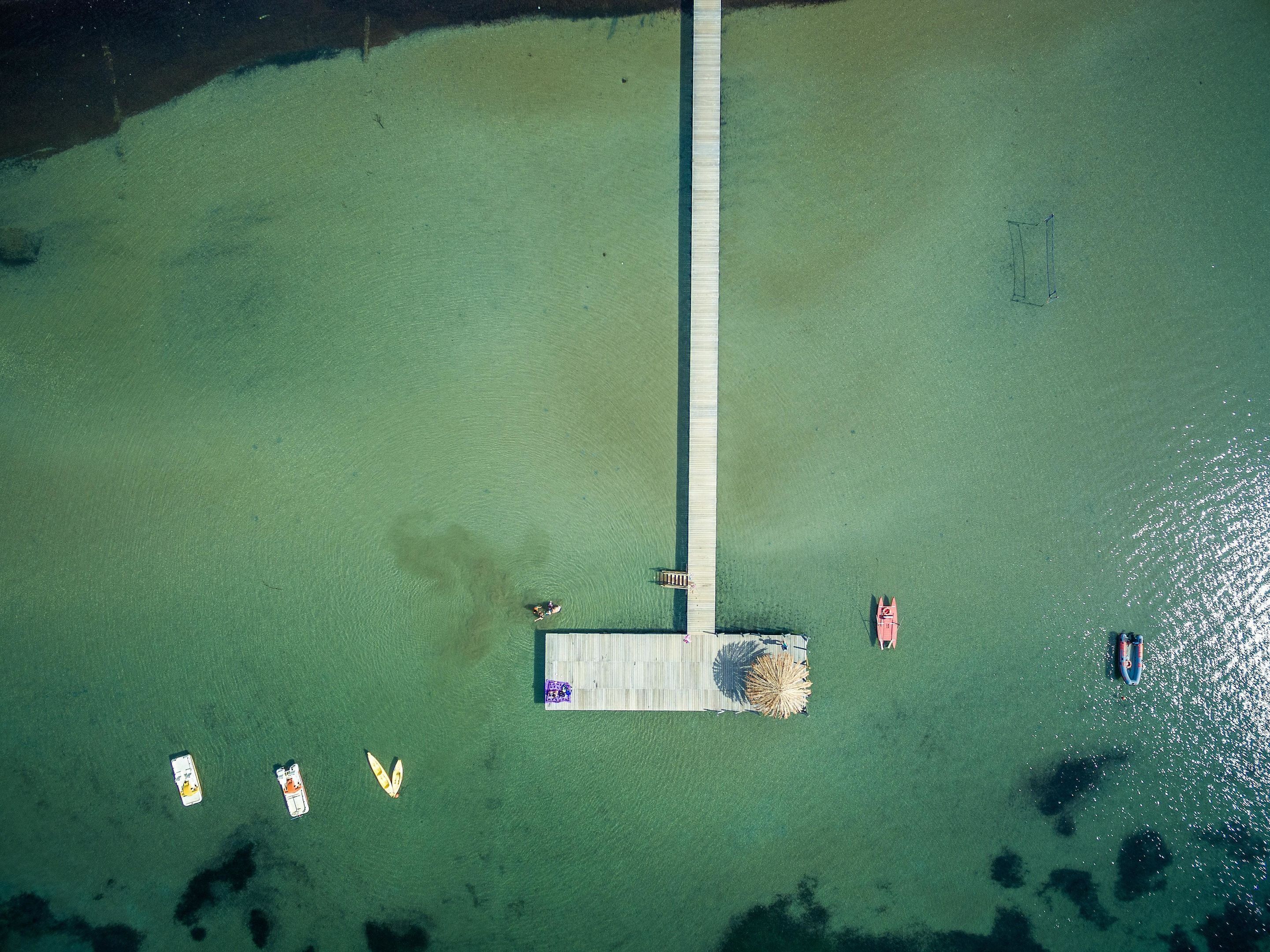 Luchtbeeld van een steiger die in het water reikt, met verschillende boten afgemeerd aan het einde.