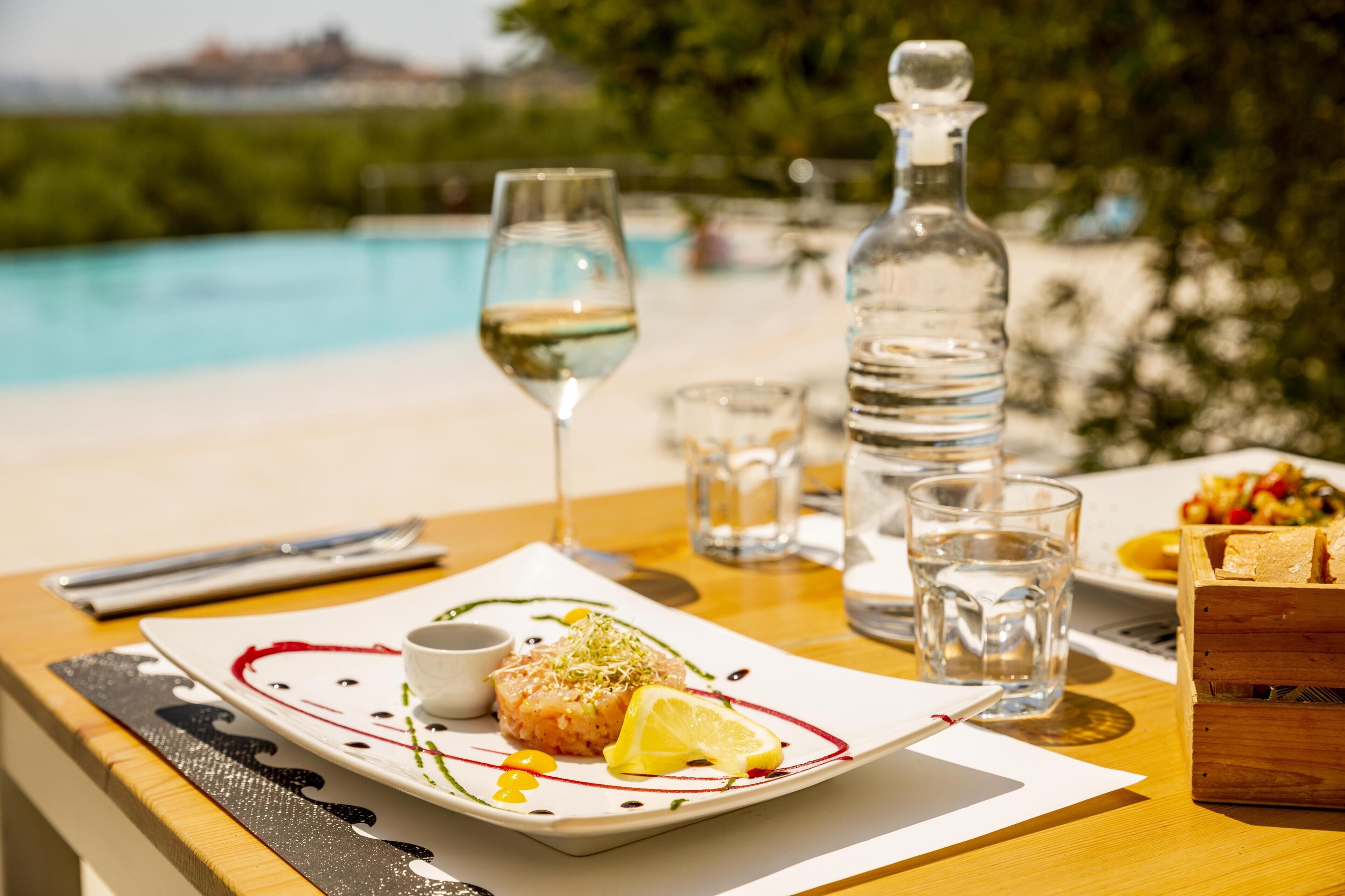A dining table with a plate of food, a bottle of water, and glasses.