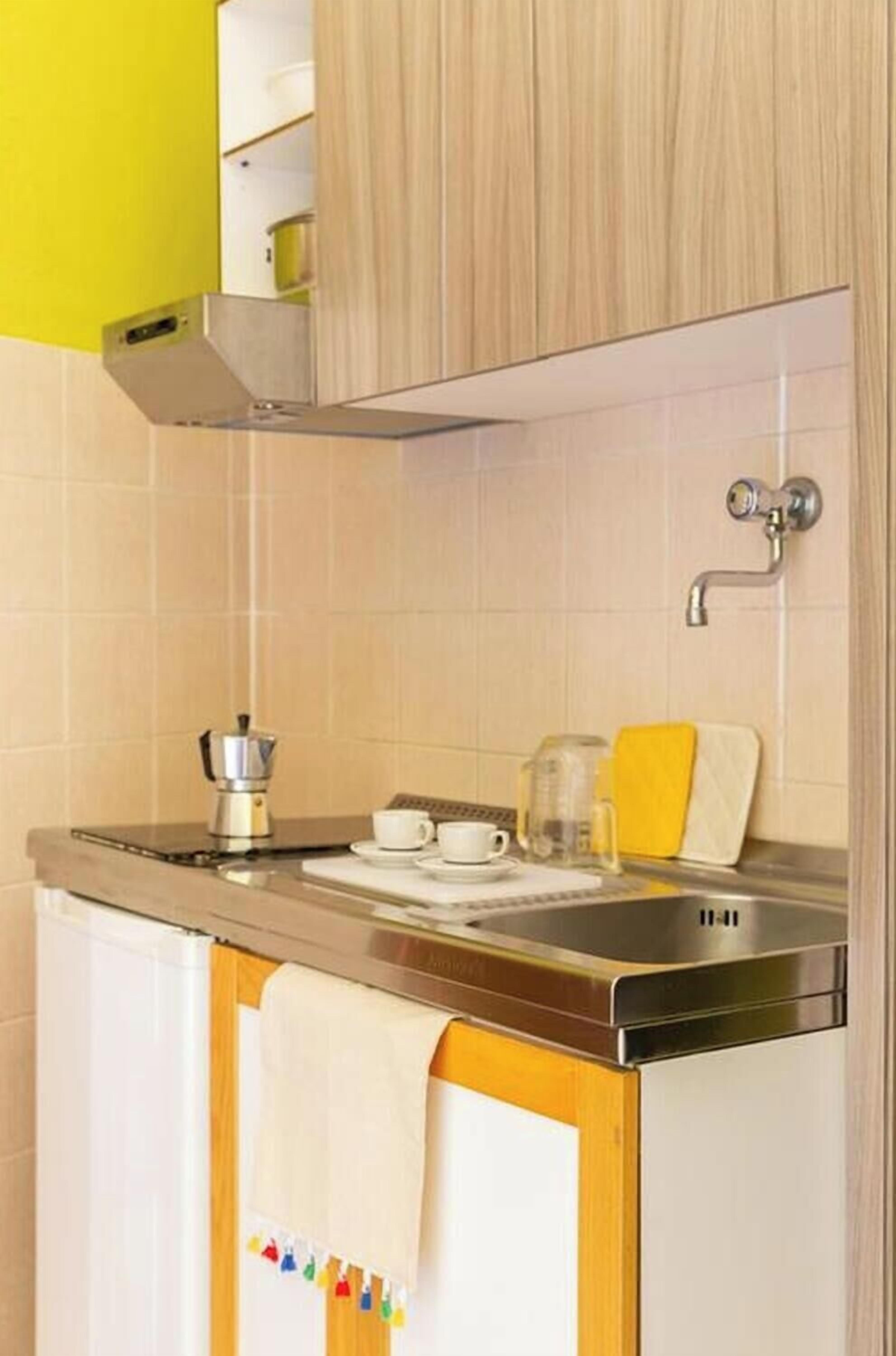 Una cucina con una macchina per il caffè, tazze e un lavandino.