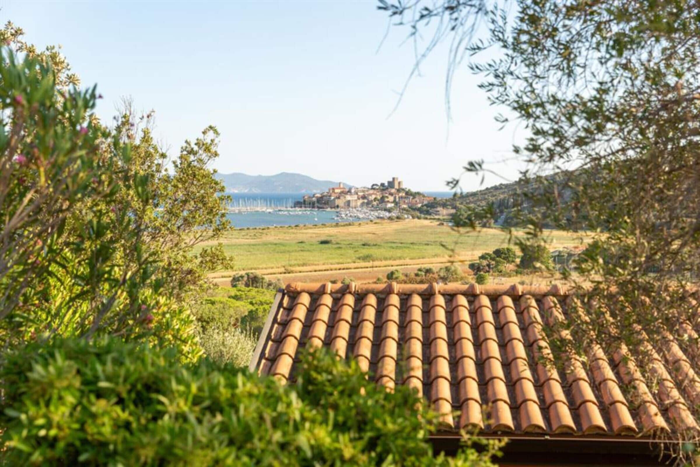 A villa with a tiled roof overlooking a coastal landscape with a village in the distance.