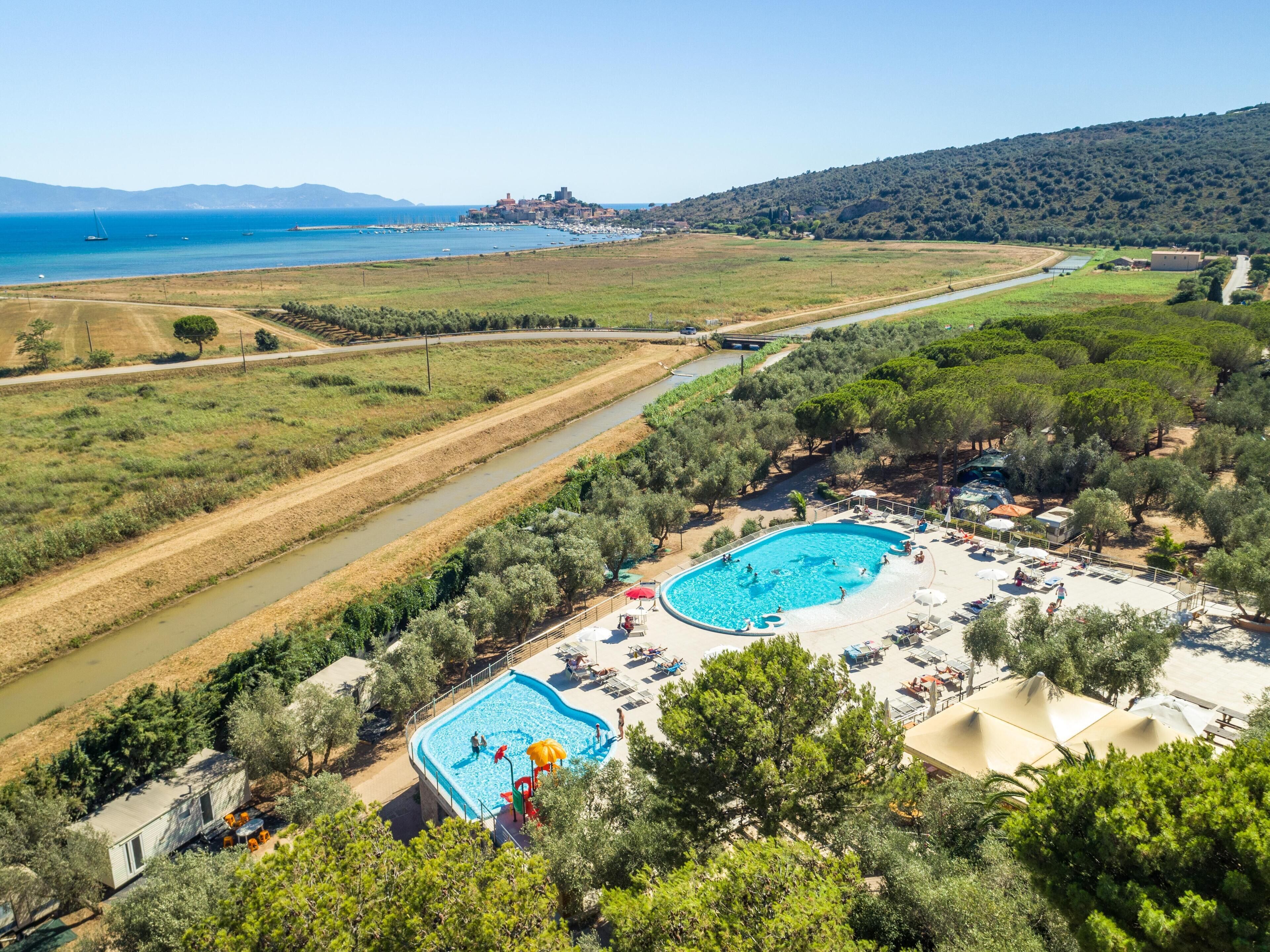 Et resort med to swimmingpools, en strand og udsigt til havet og bakkerne.