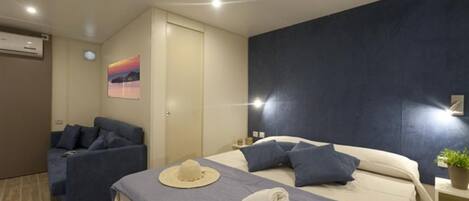 Ein modernes Hotelzimmer mit Bett, einer Couch und einem Gemälde an der Wand.