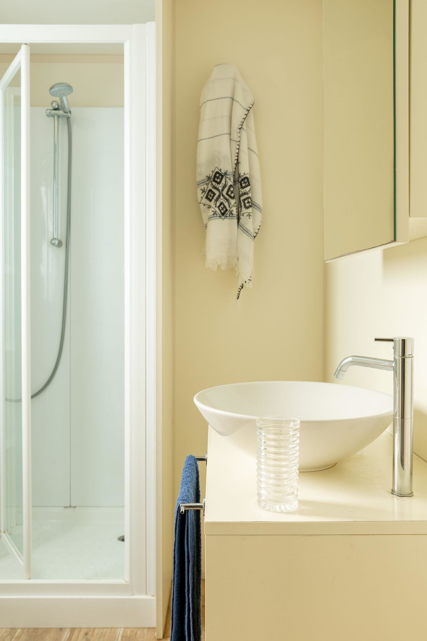 A bathroom with a glass shower enclosure, a white sink, and a towel rack.