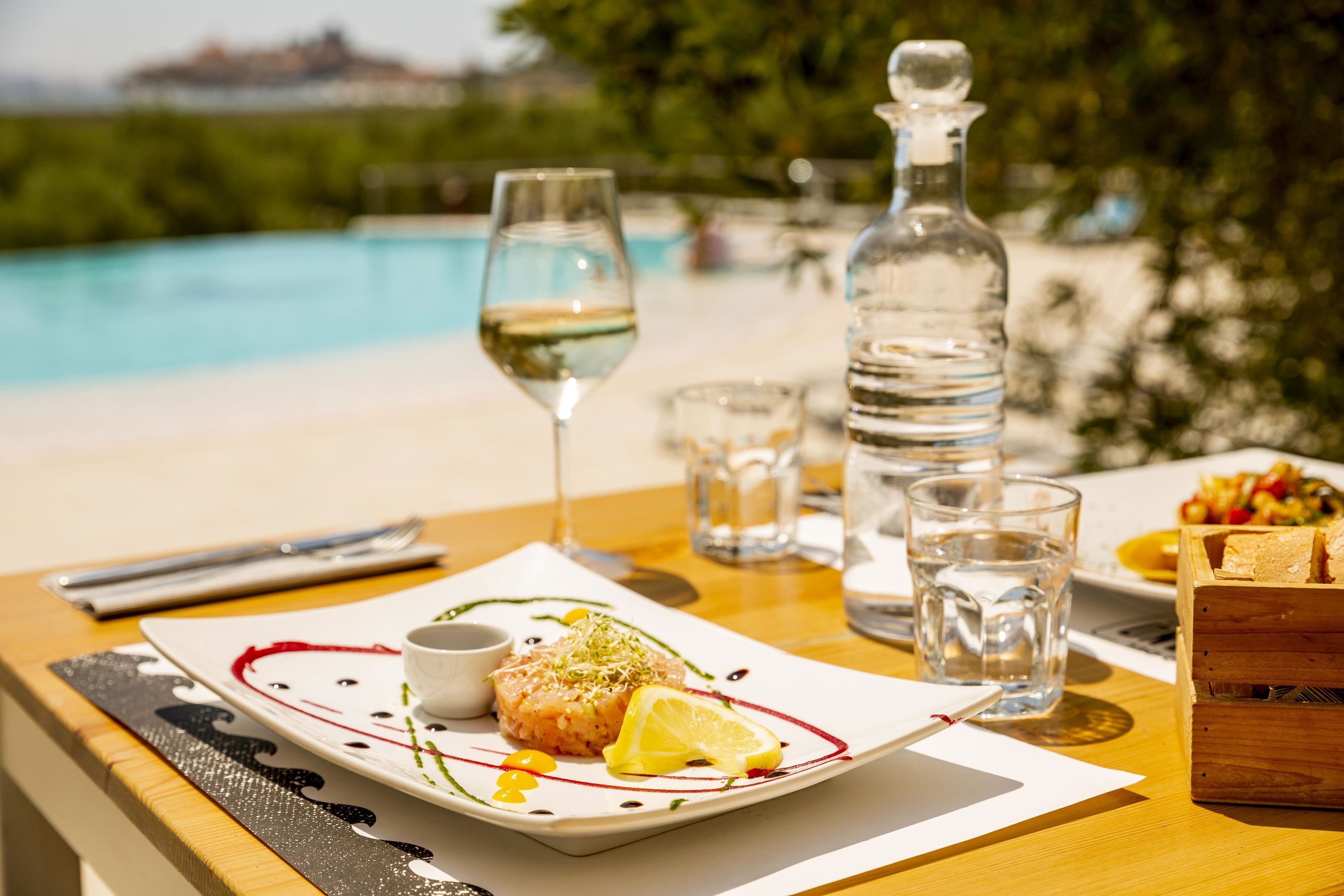 A dining table with a plate of food, glasses, and a bottle of water.