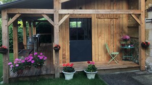 A wooden structure labeled "ATELIER" with a covered porch, potted plants, and outdoor seating. - Domaine de la Haute Poignandière (Saint-Germain-de-la-Coudre)