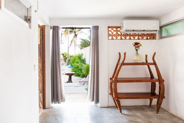A hallway with a wooden shelf, a potted plant, and a view of the outdoor area.