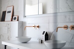 A modern bathroom with two white ceramic sinks, a single faucet, and a mirror above. - Villa Paradis (Koksijde)