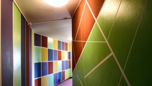 A hallway with colorful walls and a patterned carpet. - Colors Hostel (Toscolano Maderno)