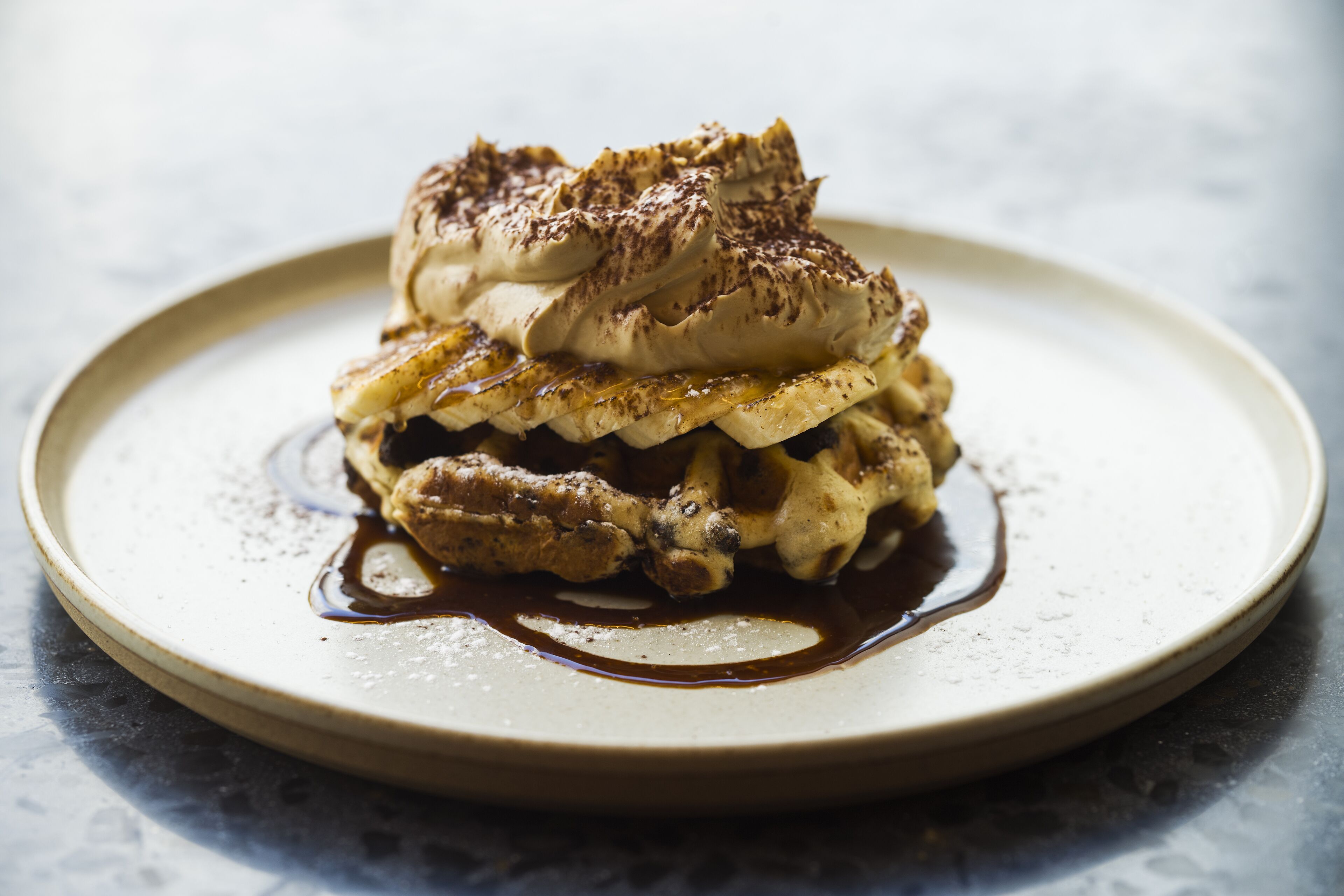 A dessert on a plate with whipped cream and chocolate sauce.