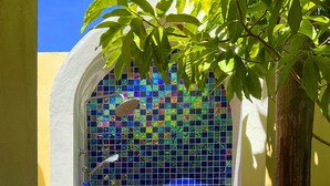 Un baño con pared de mosaico azul, una ducha y dos cuencos decorativos.