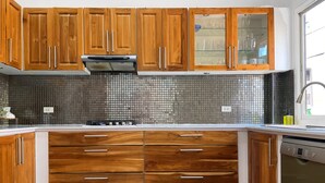 Una cocina con armarios de madera, salpicadero azulejado y lavavajillas empotrado.