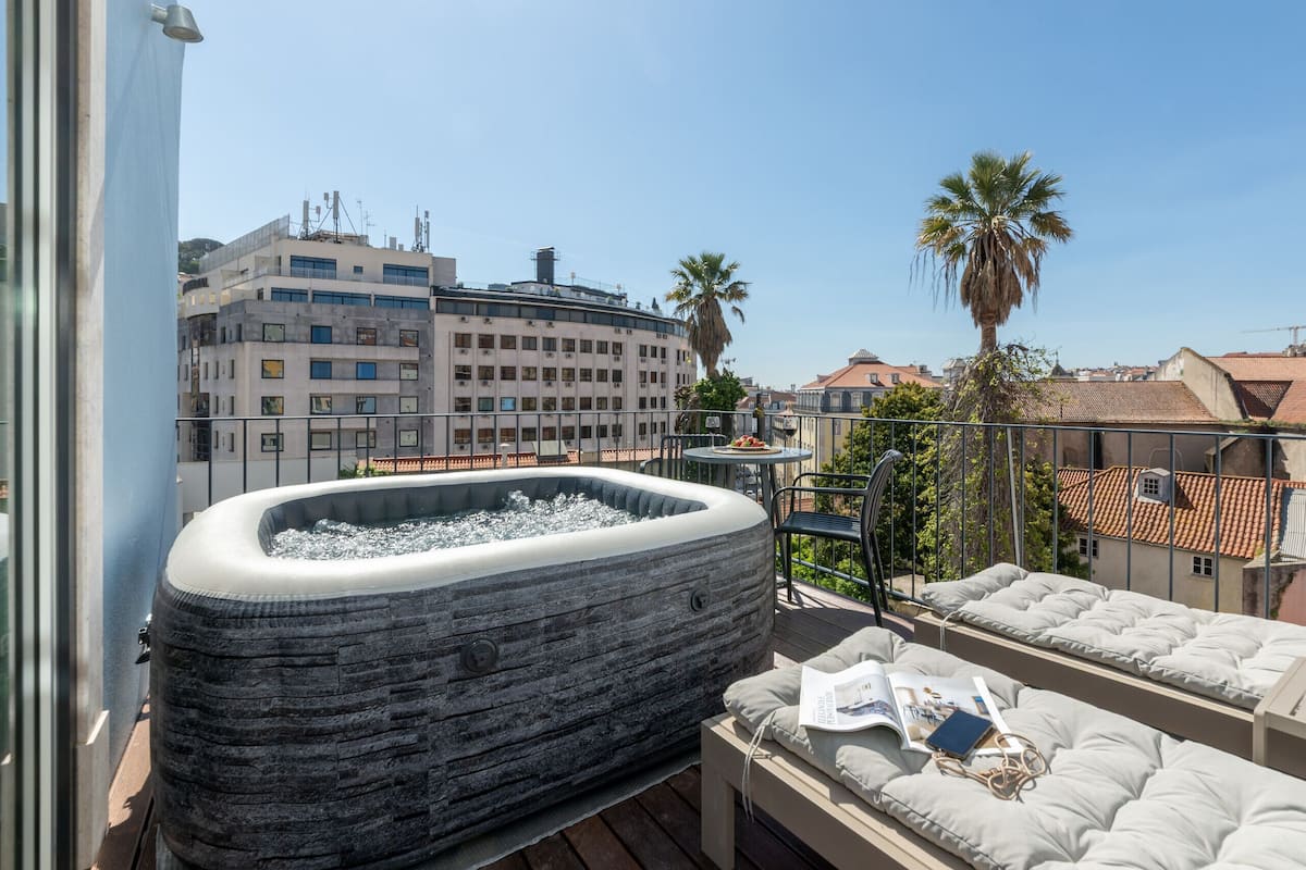 Un jacuzzi sur un balcon avec vue sur des immeubles et un palmier.