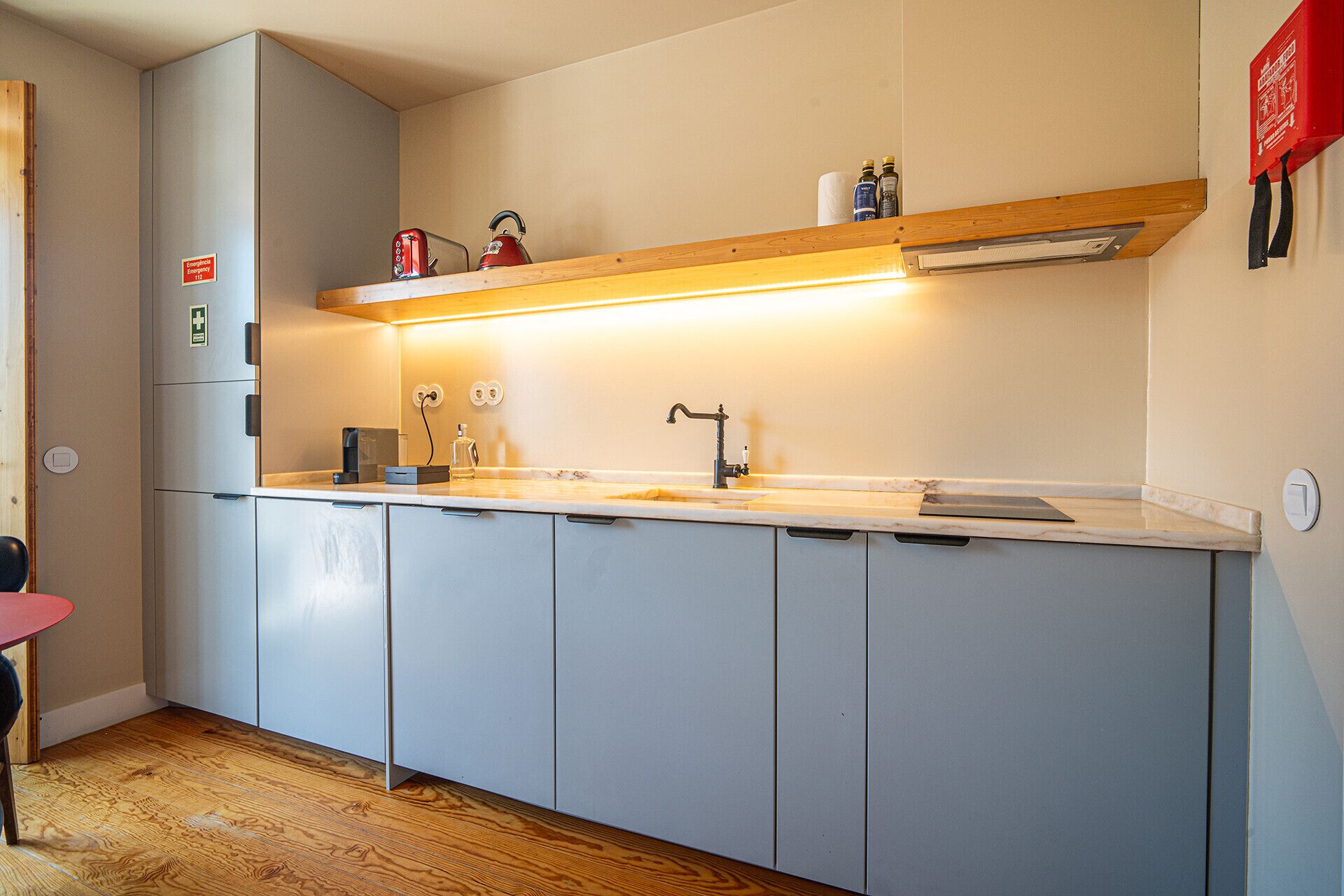 A modern kitchen with grey cabinets, a stainless steel refrigerator, a wooden countertop, and a built-in oven.