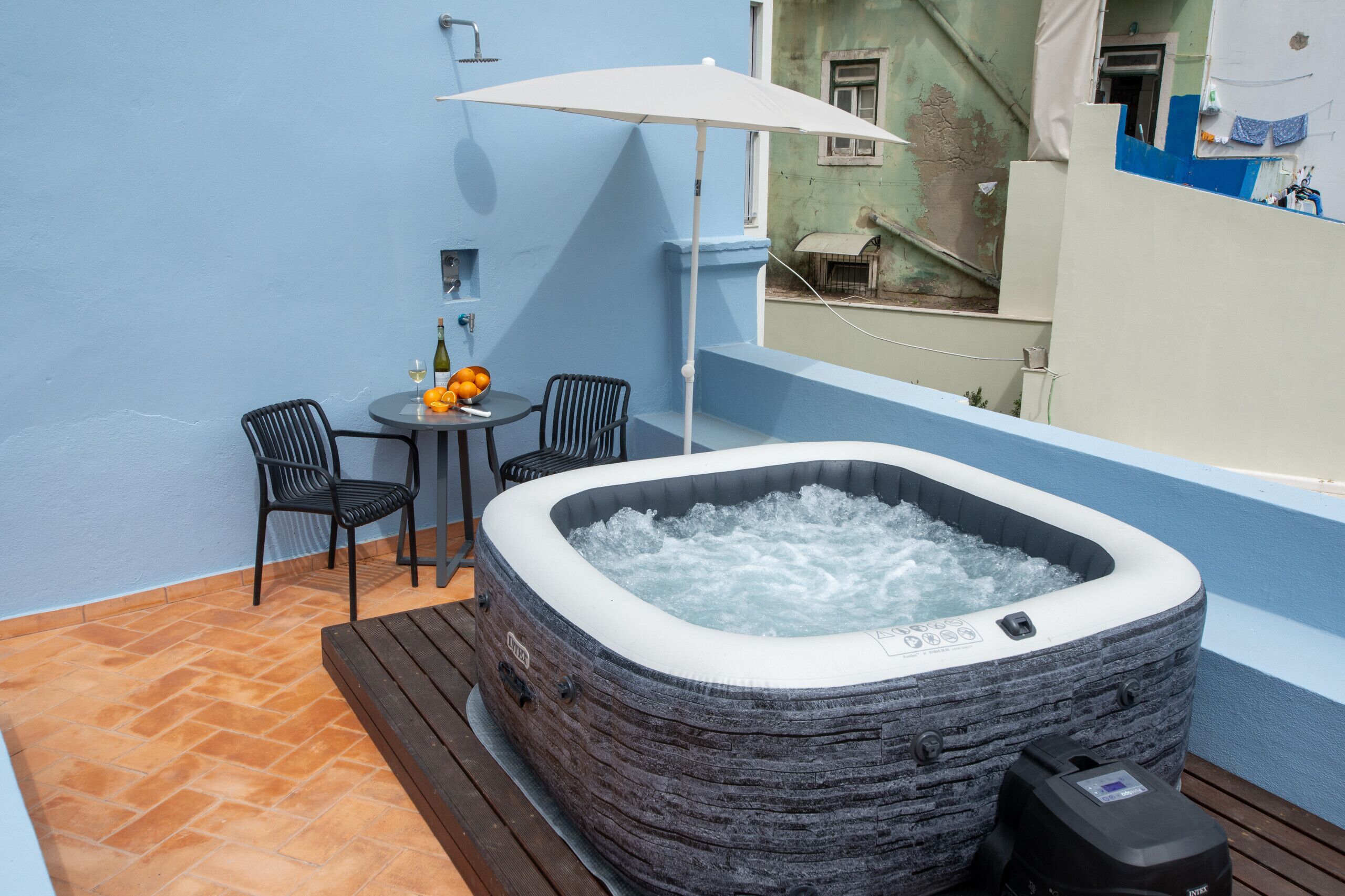 Ein Whirlpool mit Holzterrasse, Tisch und Stühlen sowie einer Weinflasche.
