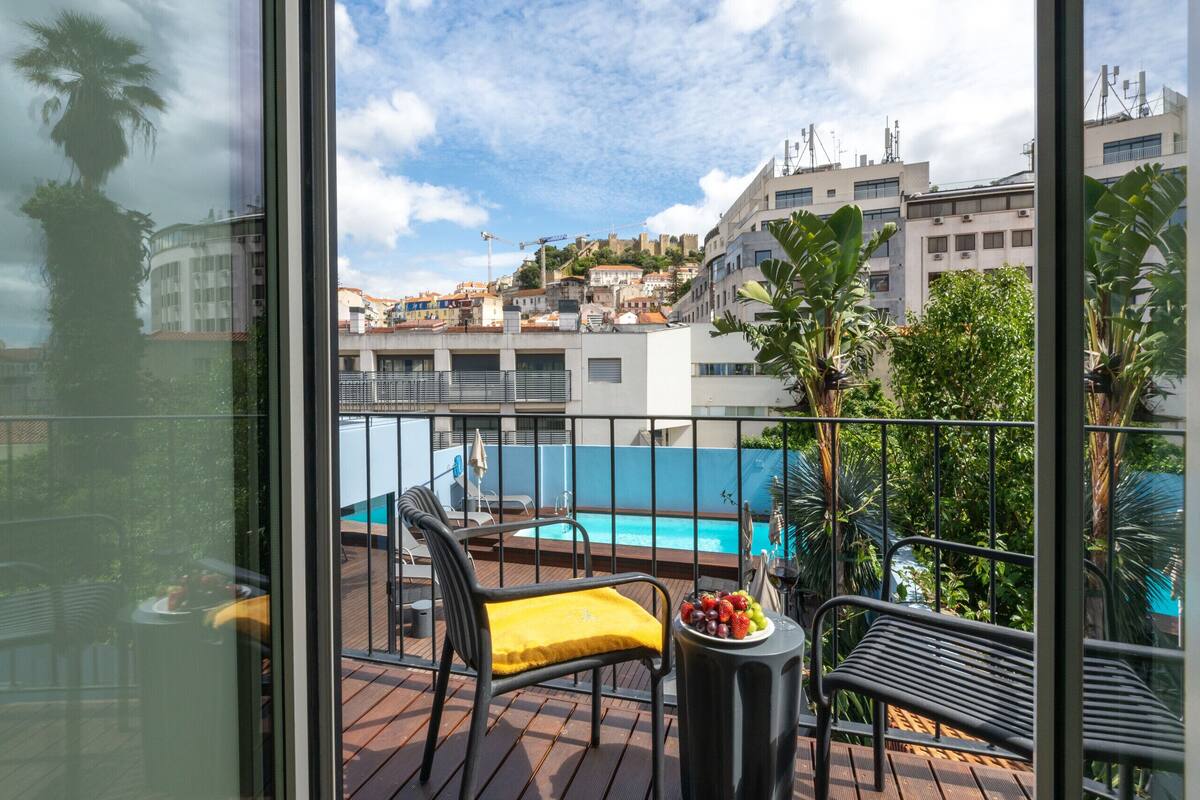 Un balcon avec une piscine, des chaises et une table sur laquelle sont disposés des fruits.