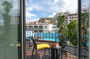 Un balcon avec une piscine, des chaises et une table sur laquelle sont disposés des fruits.