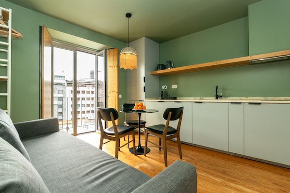 Une cuisine moderne avec un coin repas, un canapé et une vue sur l’extérieur grâce à une porte vitrée.