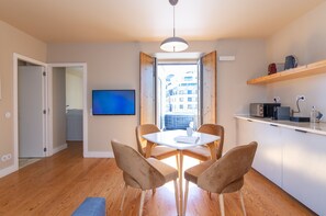 A modern apartment with a dining area, kitchen, and a TV mounted on the wall. - Light Blue Apartments - Downtown Lisbon (Lisbon)