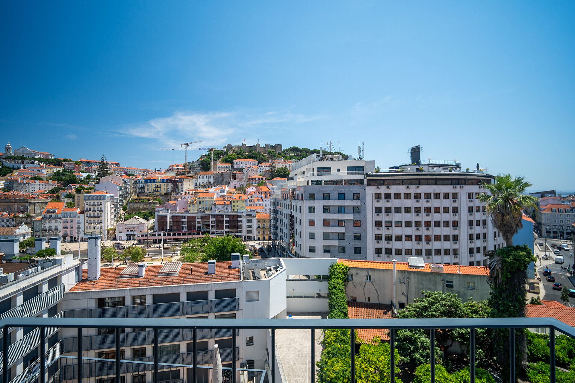 A cityscape with a mix of historic and modern buildings, a prominent white building with a curved roof, and a view of the sea.