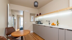 Une cuisine moderne avec une table et des chaises en bois, un plan de travail avec un évier et un luminaire suspendu.