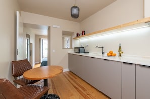 Een moderne keuken met een houten tafel en stoelen, een aanrecht met een spoelbak, en een hanglamp.
