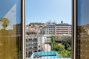 Ein Hochhaus mit mehreren Etagen, Balkonen und einem Pool, der durch ein Fenster sichtbar ist.