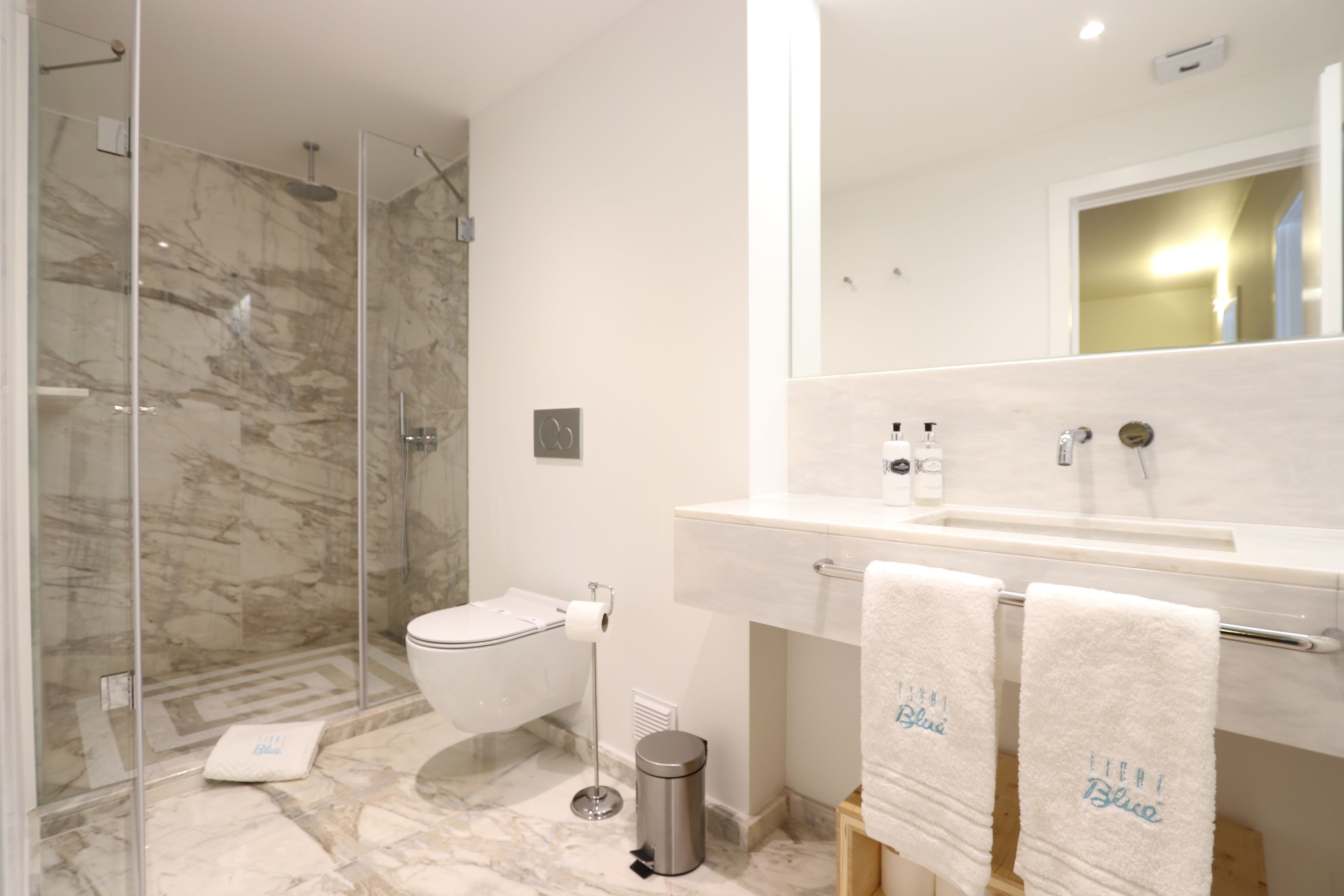 Un bagno moderno con doccia vetrata, un water e un mobile lavabo con due asciugamani appesi.