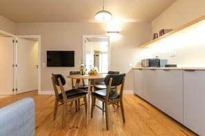 A compact kitchen with a dining table, chairs, a flat-screen TV, and a built-in oven.