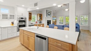 Une cuisine moderne avec des meubles blancs, des appareils en acier inoxydable et un grand îlot central.
