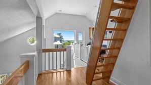 Un escalier en bois menant à un balcon d’où l’on peut admirer l’océan.