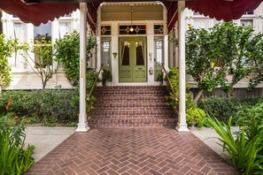 A brick-paved entrance with a green door, white columns, and a covered porch.