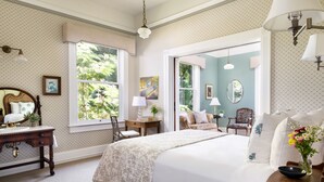 Un dormitorio con una cama grande, un aparador, un tocador y una ventana con vistas al verdor.