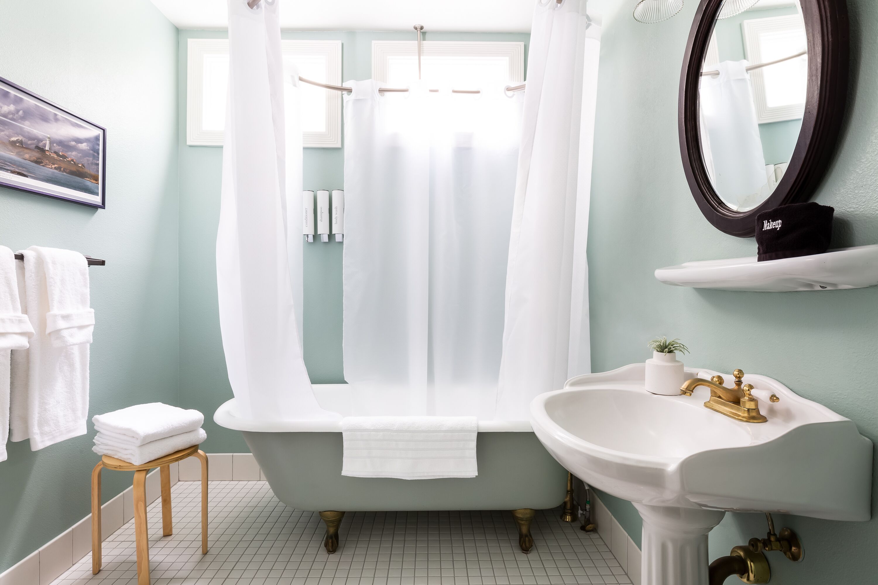 Une salle de bain avec une baignoire, un lavabo doté d’un robinet doré, un miroir et un porte-serviettes.