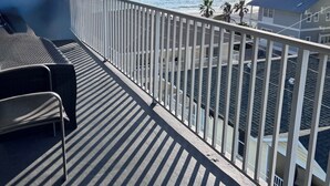 Een balkon met uitzicht op de oceaan, een stoel en een leuning.