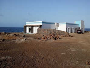 A coastal building with a stone wall and a car parked nearby. - Villa Sao Jose (Santa Cruz)