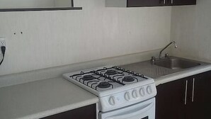 Une cuisine avec un four blanc, des meubles de couleur sombre, un plan de travail blanc et un évier.