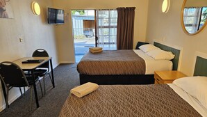 Une chambre d’hôtel avec deux lits, un bureau, une chaise, une télévision et une vue sur l’extérieur.
