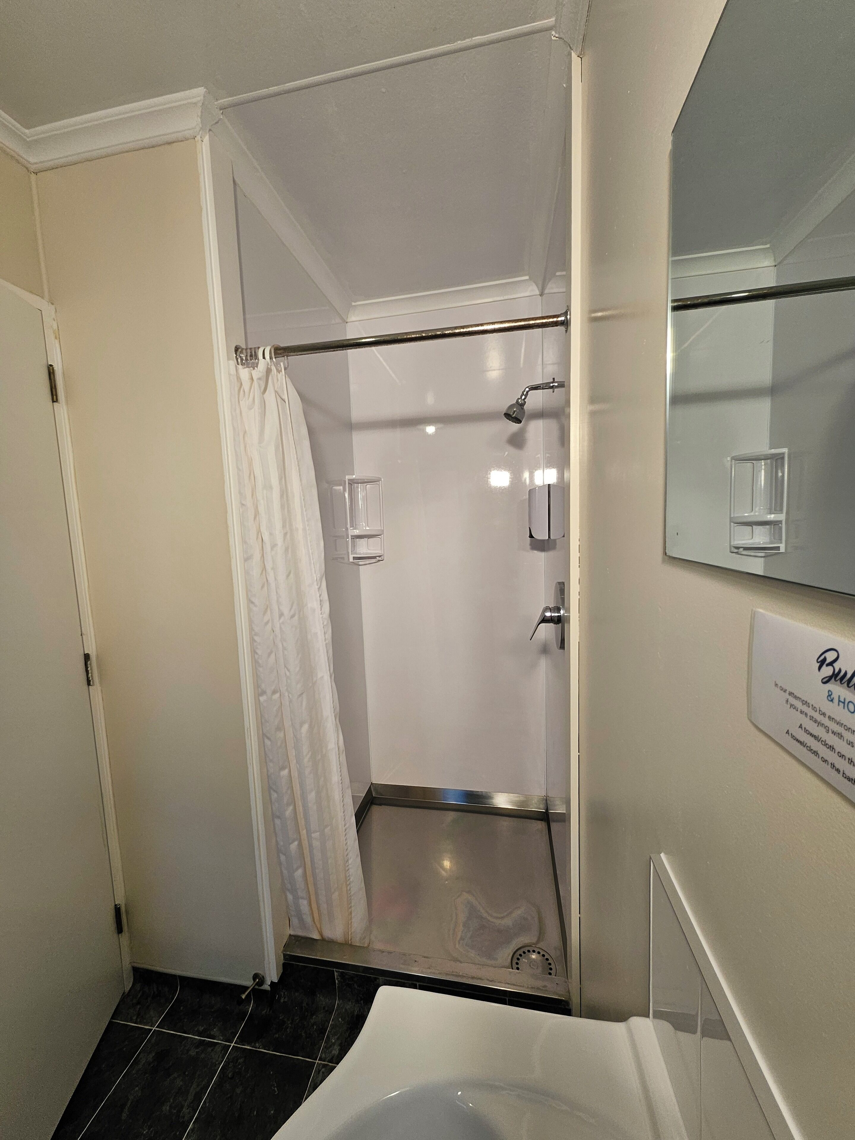 A bathroom with a shower, a toilet, and a sink. There is a towel rack and a mirror above the sink.