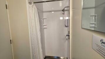 A bathroom with a shower, a toilet, and a sink. There is a towel rack and a mirror above the sink.